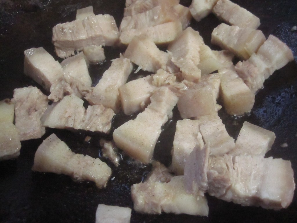 小さく切った豚の三枚肉をフライパンで炒める