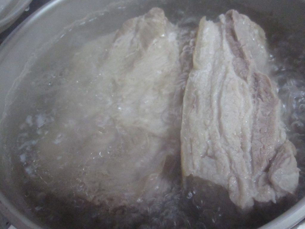 豚肉の塊を数時間かけてグツグツ煮込み茹でる様子