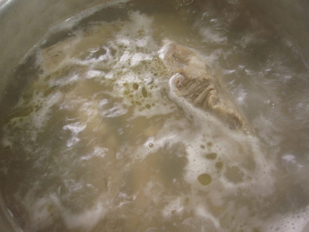 湯を沸かした鍋で骨付きソーキ豚肉をじっくりコトコト茹でる