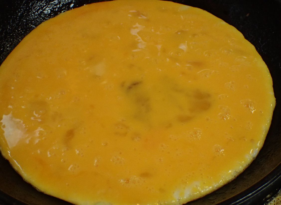 ときほぐした玉子をフライパンで焼いて卵焼きを作る