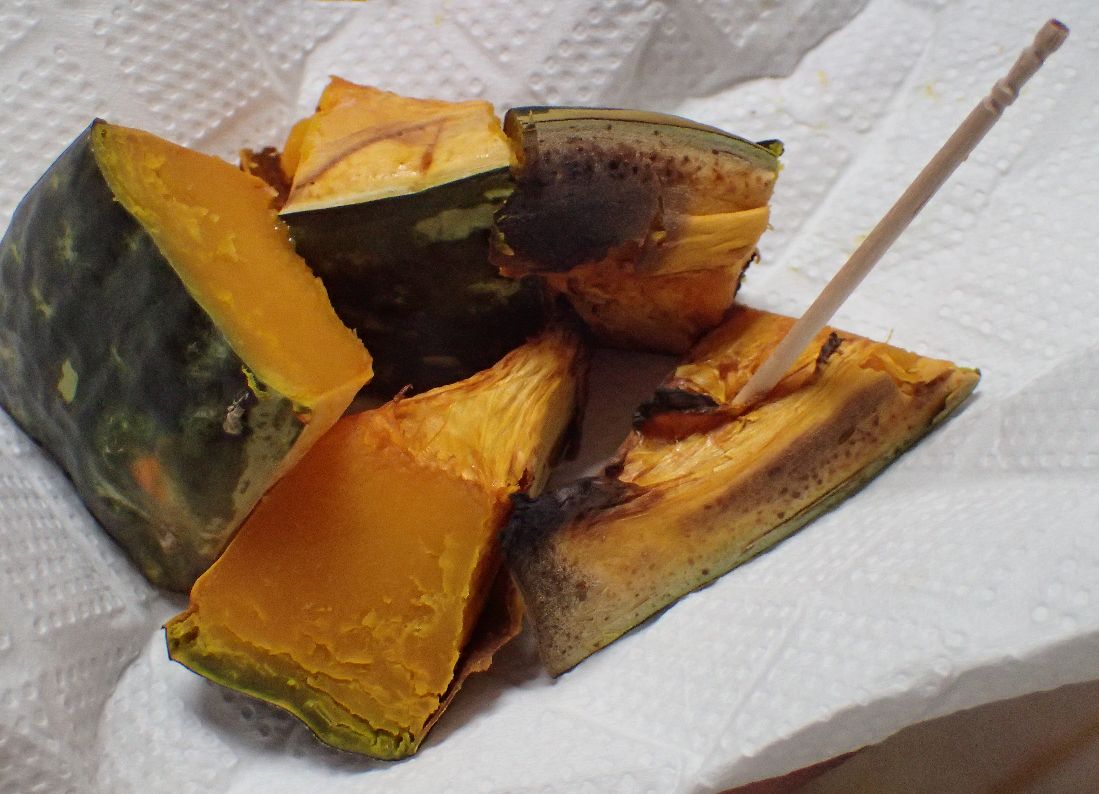 焼き上がった焼きカボチャを一口サイズに切って爪楊枝で食べる